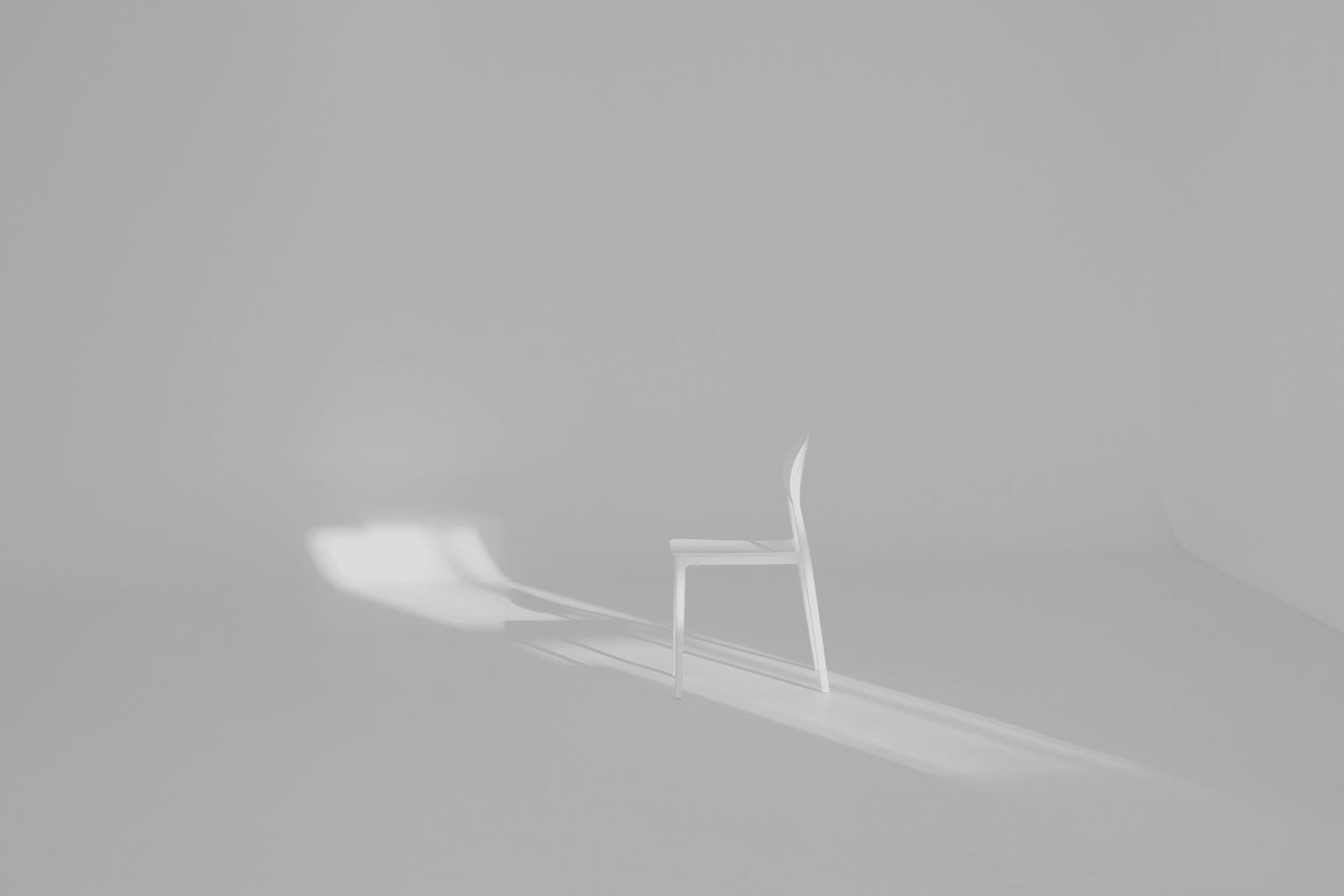 A single chair casting a long shadow across a pale floor