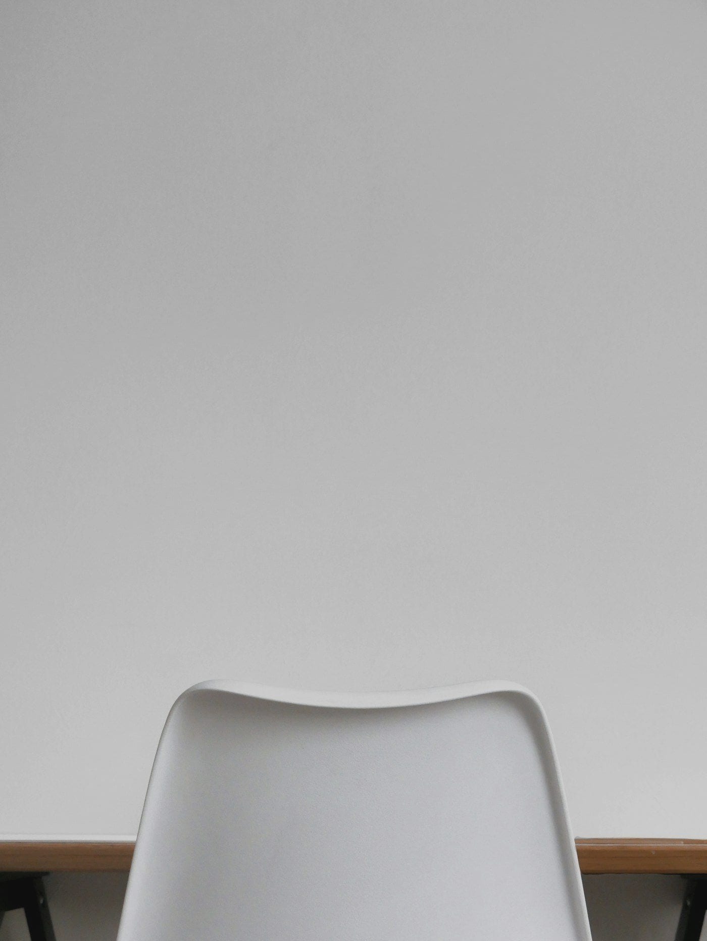 An empty consultation chair against a plain white wall in daylight